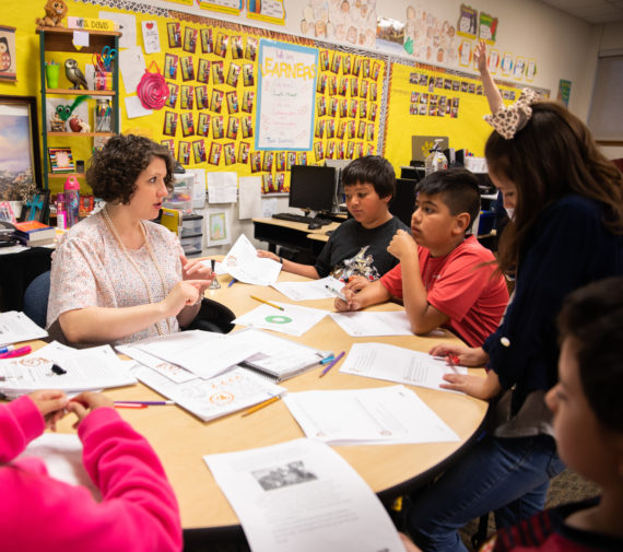 students and teacher learning around table