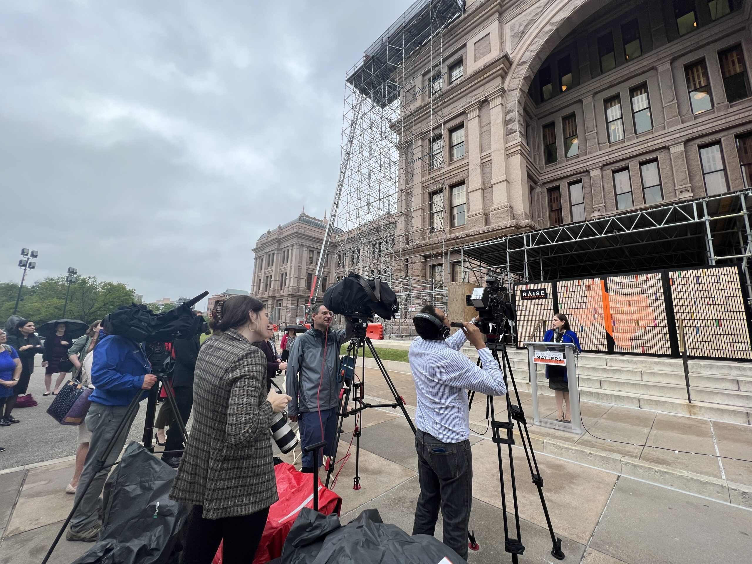 Reporters taking video and photo of press conference in front of Texas Capitol